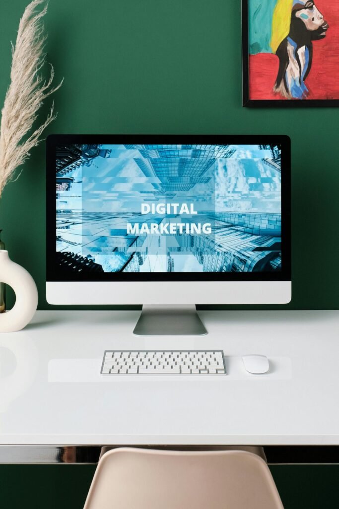 A sleek modern workspace featuring digital marketing concepts on a computer screen and artistic decorations.